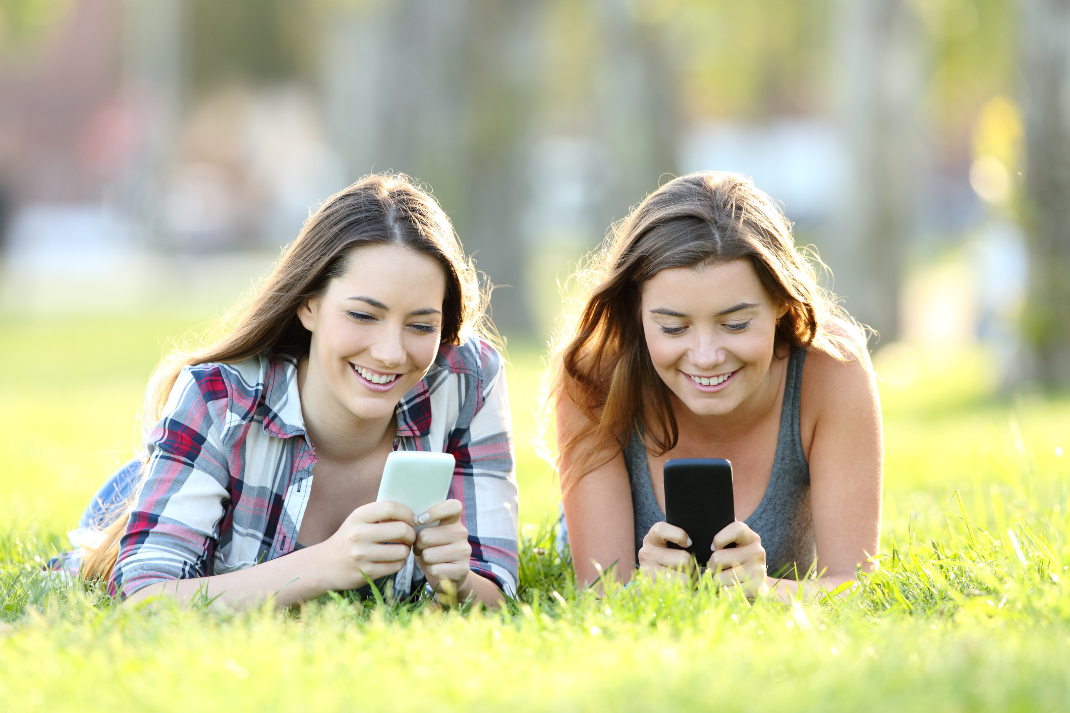 Use your friends. 2 Друга на траве английский. Teenagers using gadgets. Люди фото на траве, показывают телефоны. Teens using mobiles.