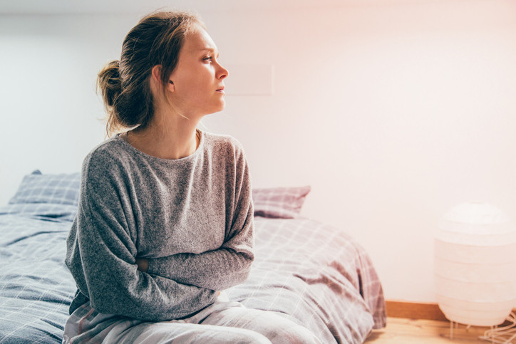 young-woman-on-bed-looks-tired-and-unwell